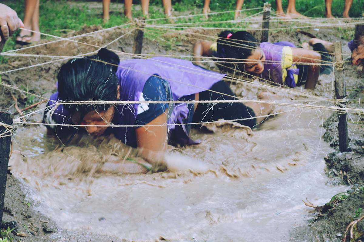 muddy water two women crawling on mud with rope wet
